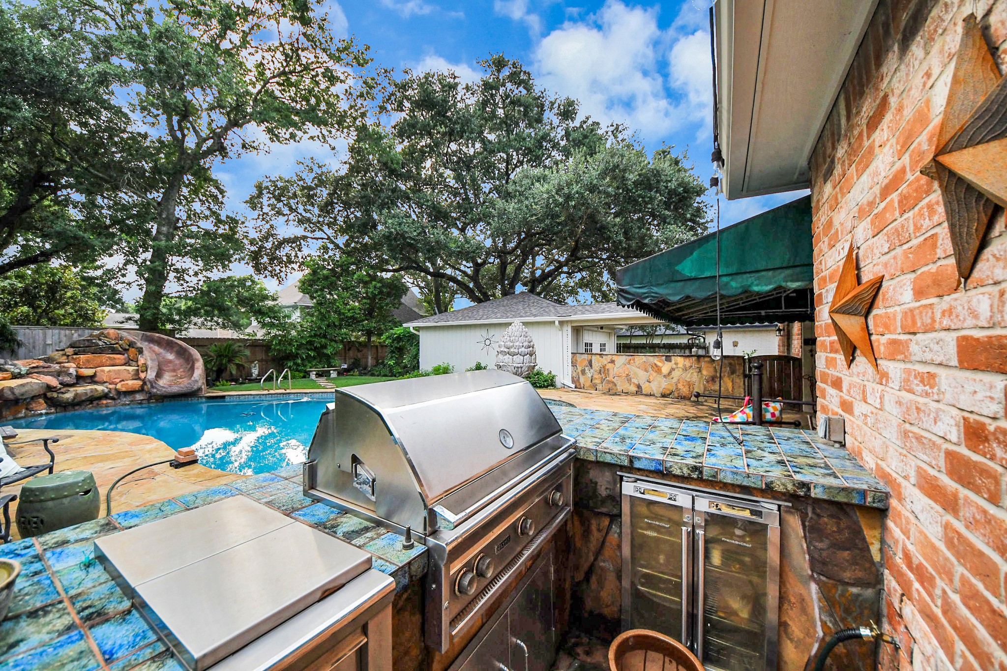 The outdoor kitchen features a built-in grill, tile surround and generous prep space, perfectly positioned for easy poolside entertaining.