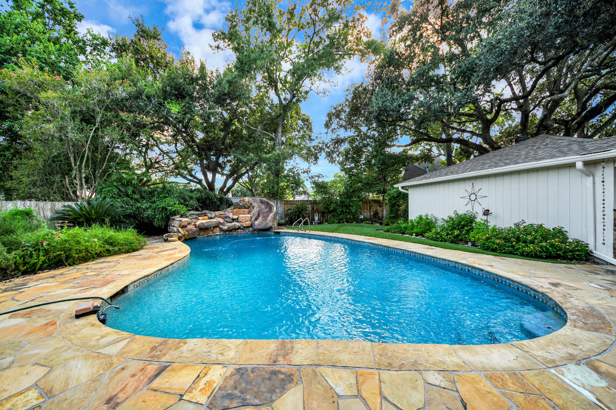 The backyard is the showstopper, with a large resort-style pool surrounded by mature trees and lush landscaping.