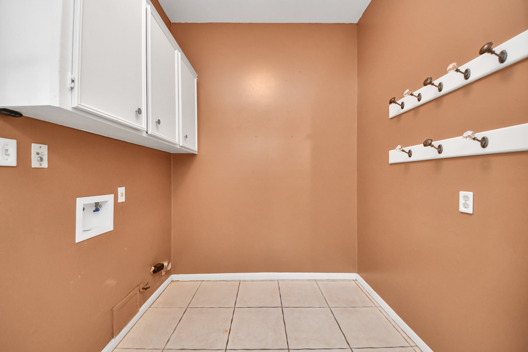 Dedicated utility room offers upper cabinetry, hanging space and room for a full-size washer and dryer.