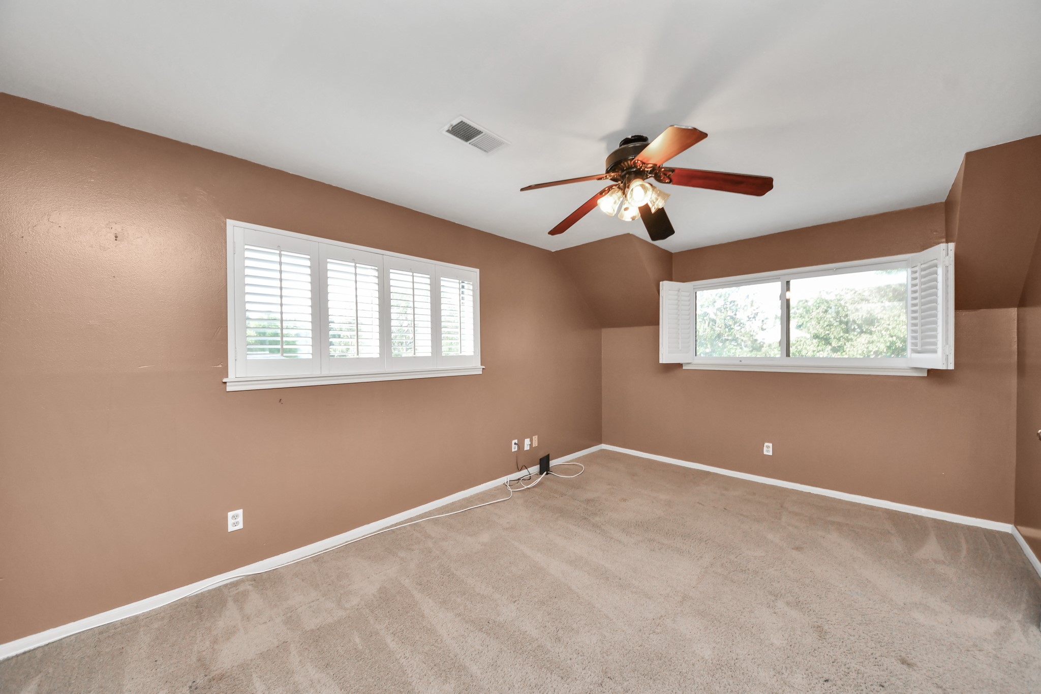 Upstairs bedroom offers a generous footprint, multiple windows and plantation shutters.