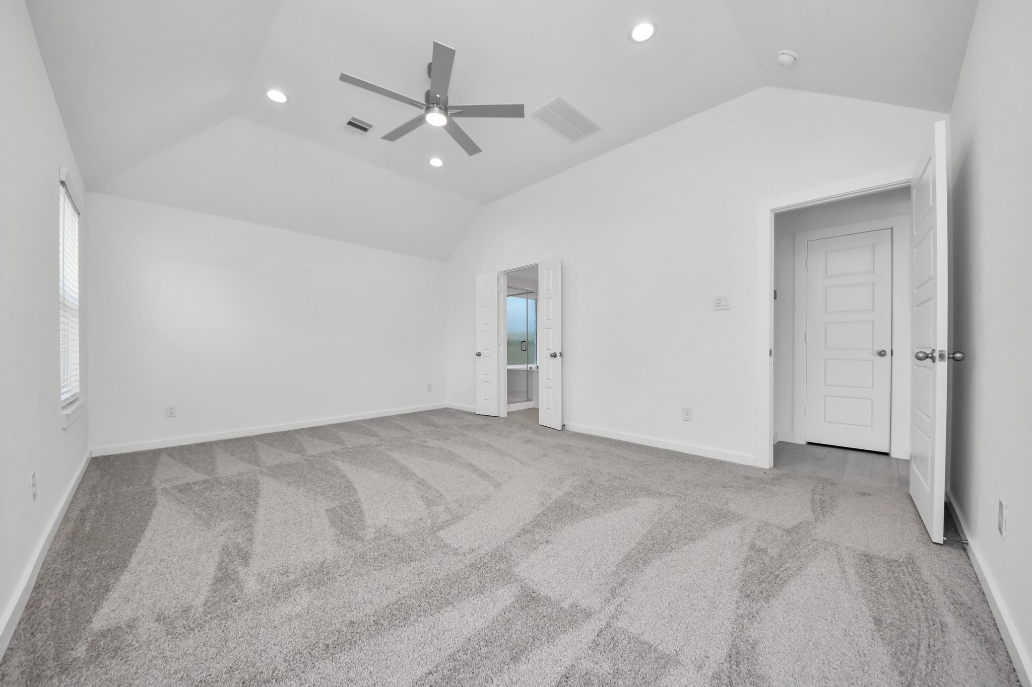 Escape and relax in the exquisite primary suite, a haven to unwind after a long day. The spacious room, boasts plush carpeting, soothing paint tones, high ceilings, and expansive windows adorned with privacy blinds. Sample photo of completed home with similar floor plan. Actual colors and selections may vary.