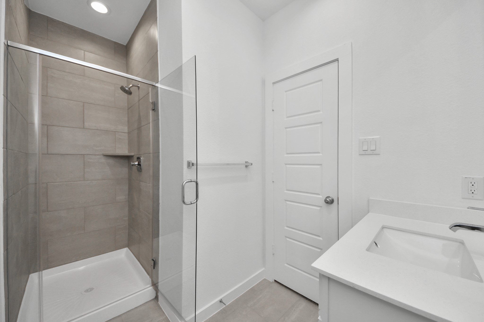 Secondary bath features tile flooring, walk-in shower with tile surround, light stained wood cabinets, beautiful light countertop. Sample photo of completed home with similar floor plan. Actual colors and selections may vary.