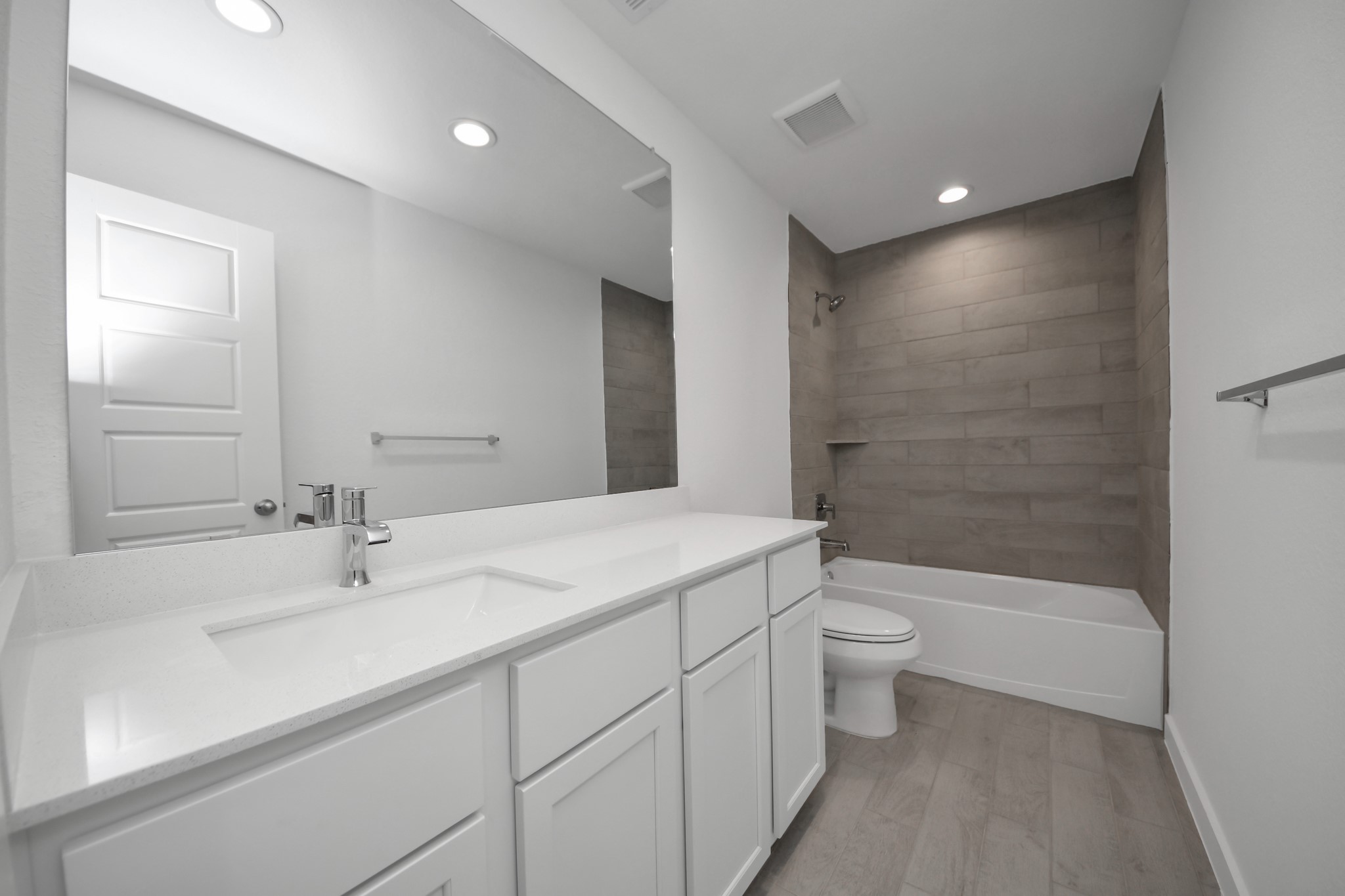 Secondary bath features tile flooring, bath/shower combo with tile surround, light stained wood cabinets, beautiful light countertop. Sample photo of completed home with similar floor plan. Actual colors and selections may vary.
