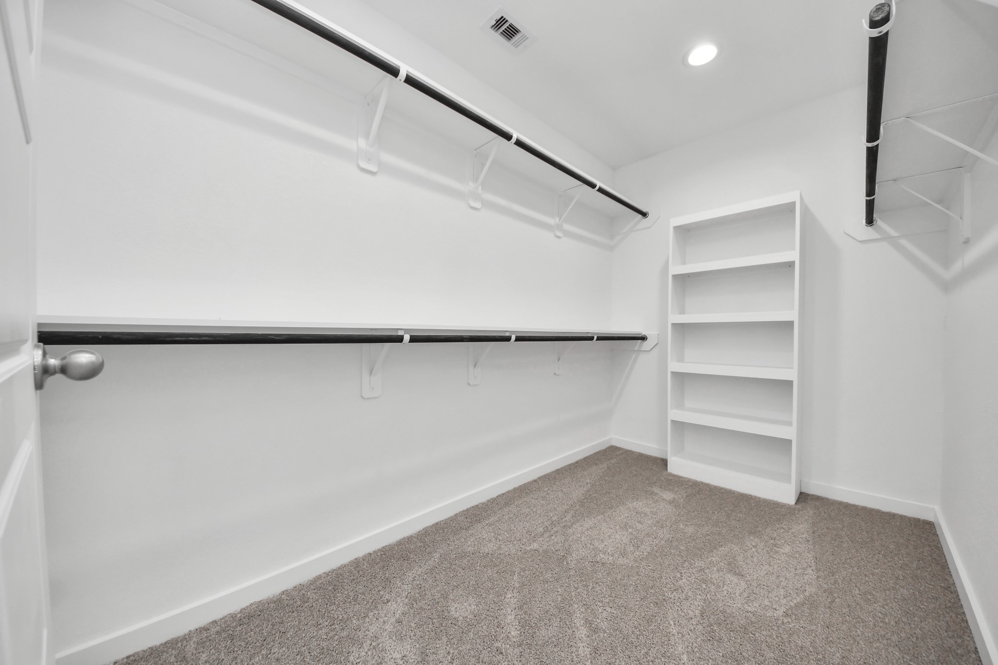 Walk-in closet that epitomizes luxury and practicality. This generously sized space features built-in shelving, offering abundant room for impeccable organization. High ceilings and recessed lighting create a bright and welcoming ambiance. v