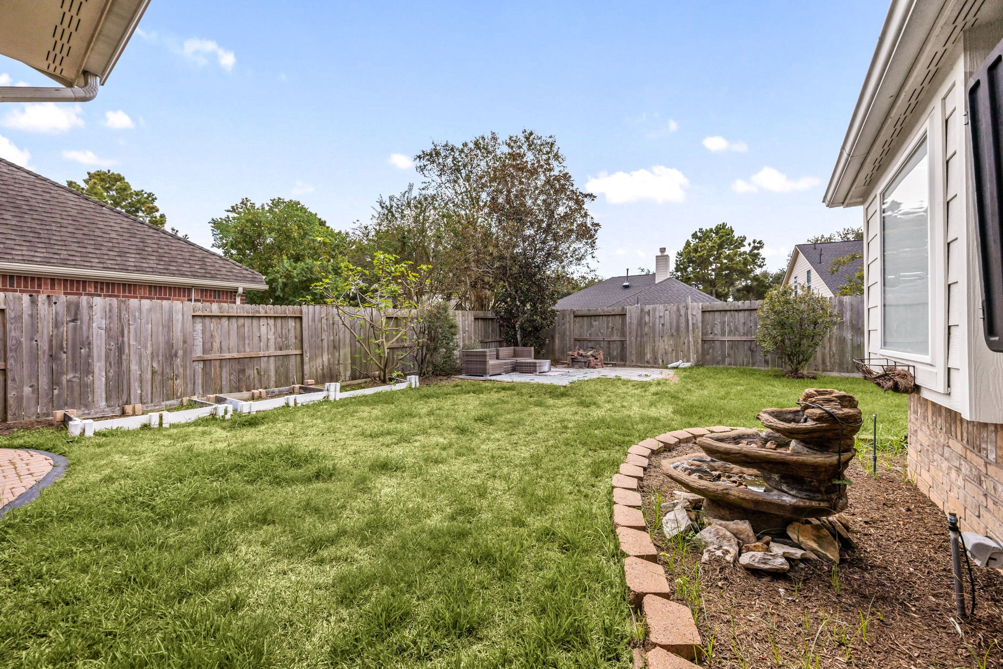 Spacious fenced backyard featuring a large grassy area, mature landscaping, and plenty of room for outdoor activities.