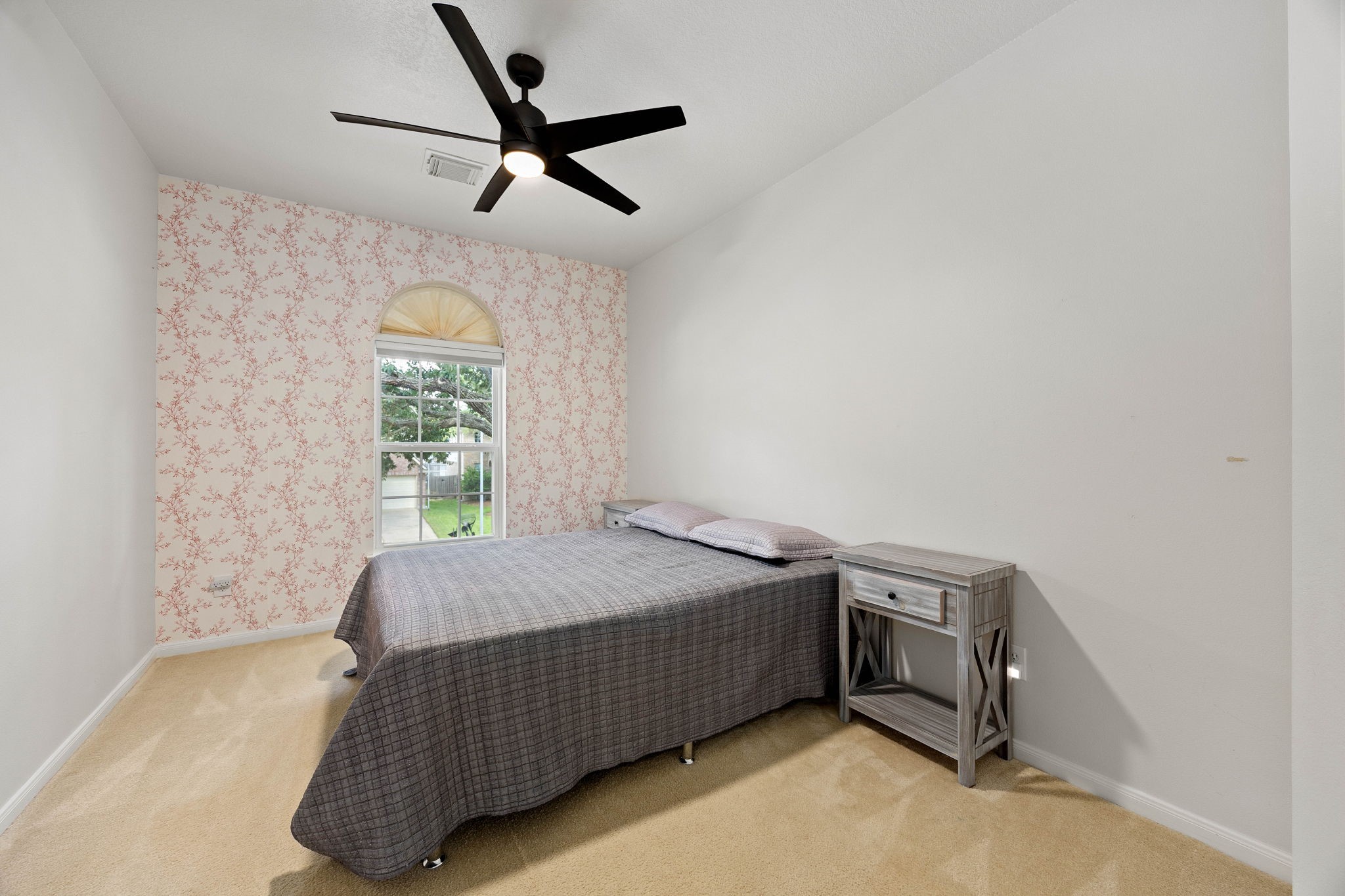 Secondary bedroom featuring a ceiling fan, natural light, and comfortable space for bedroom furnishings.