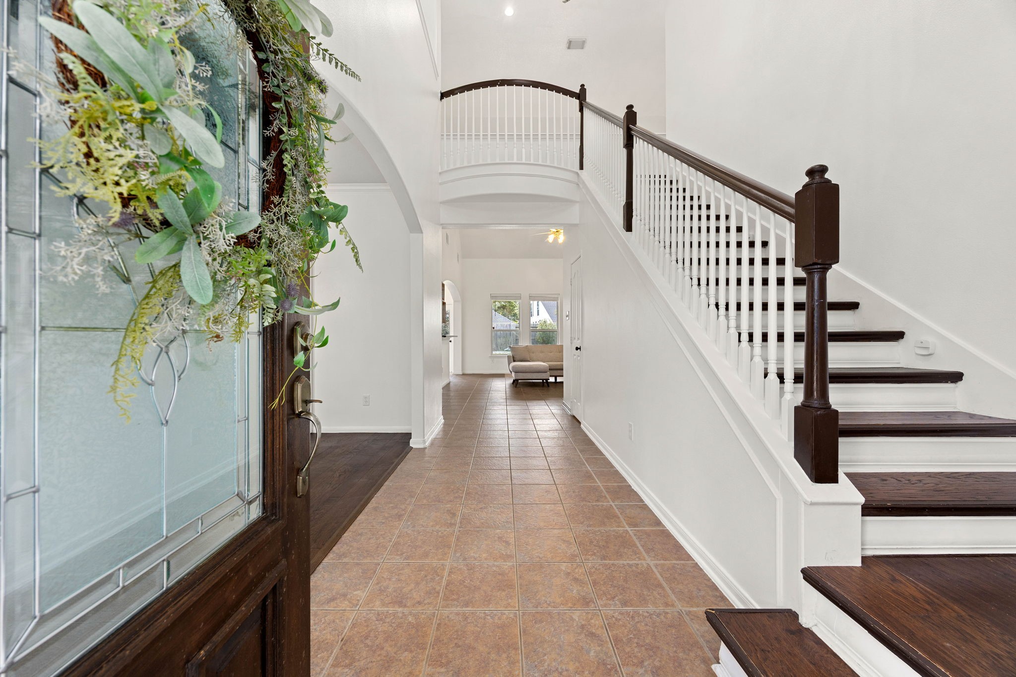Inviting entry hallway featuring wood-look flooring, a staircase with contrasting railing, and a view toward the living areas.
