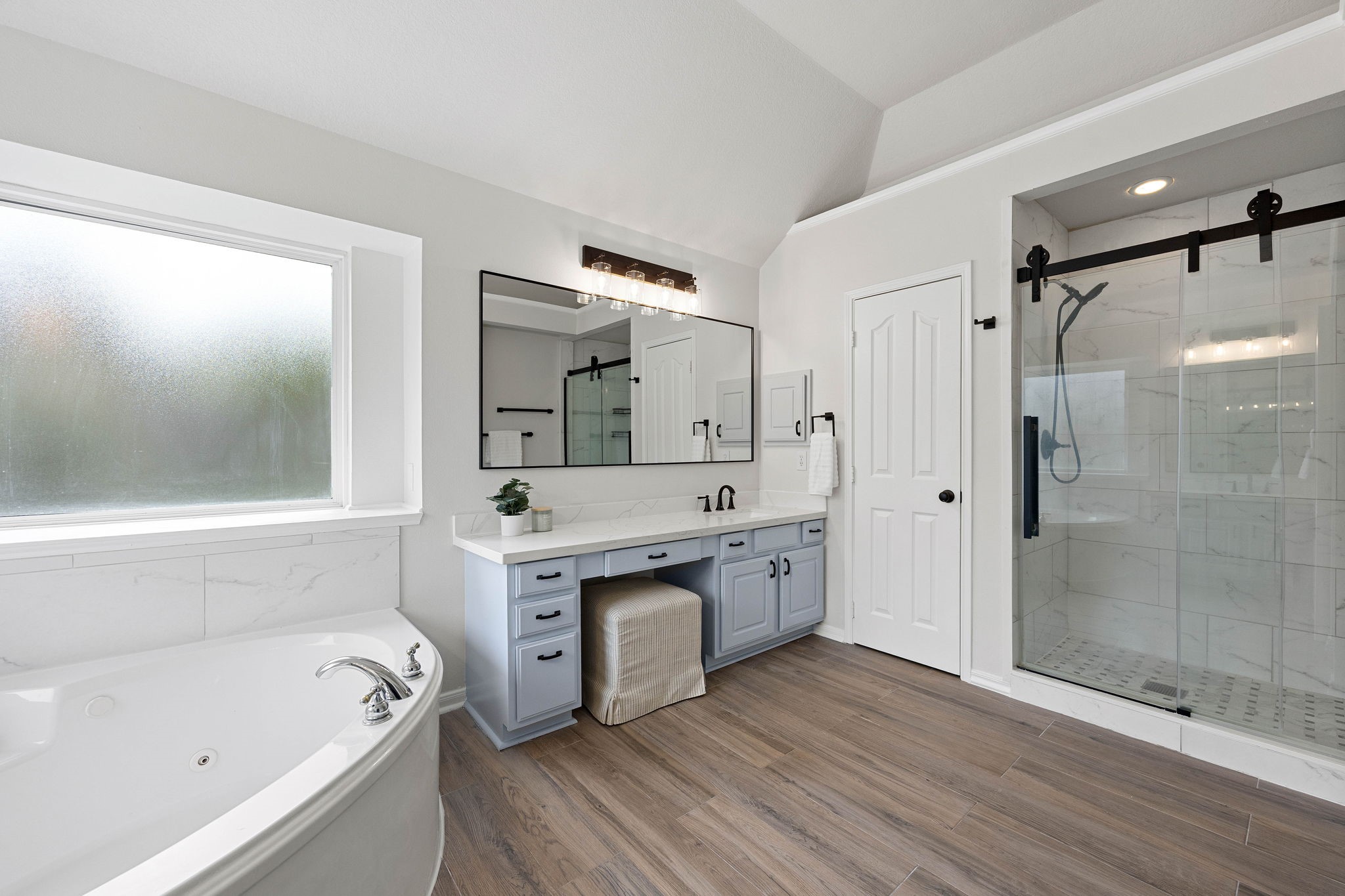 Primary bathroom featuring a soaking tub, separate shower, dual vanity area, and abundant natural light.