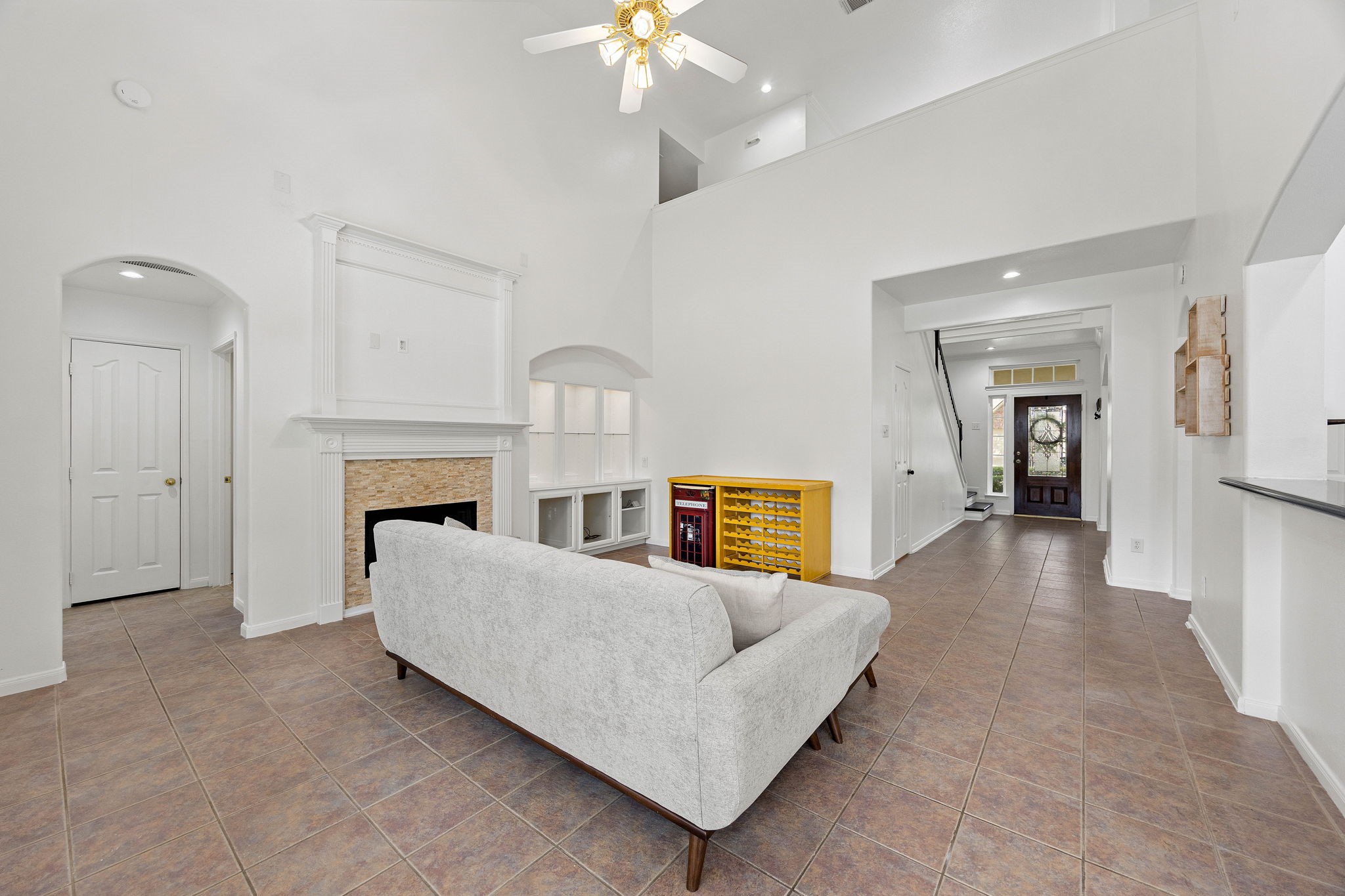 Spacious living room featuring a fireplace, ceiling fan, neutral finishes, and an open connection to the kitchen.