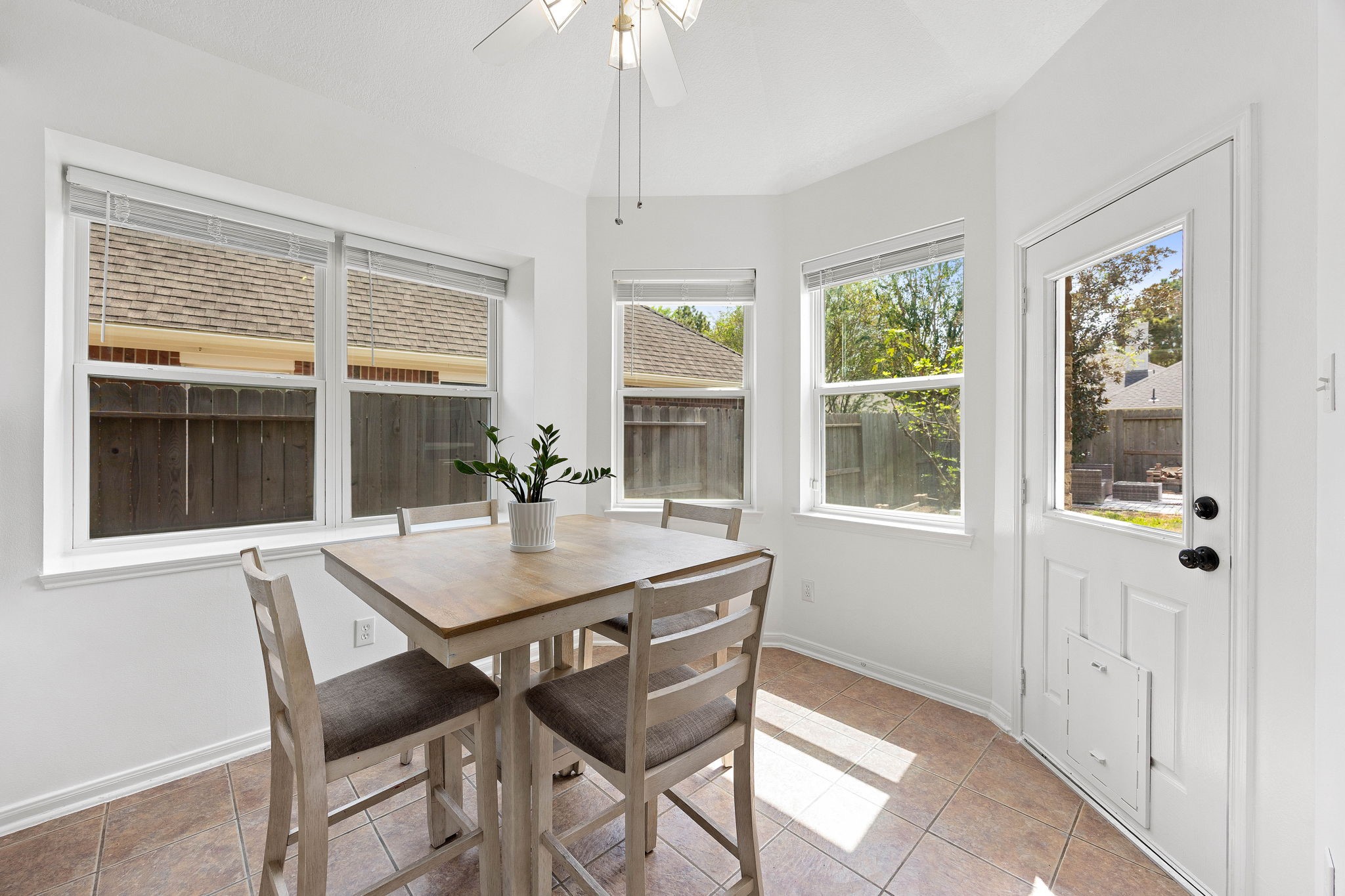 Sun-filled breakfast nook featuring multiple windows, tile flooring, and direct access to the outdoor living area.