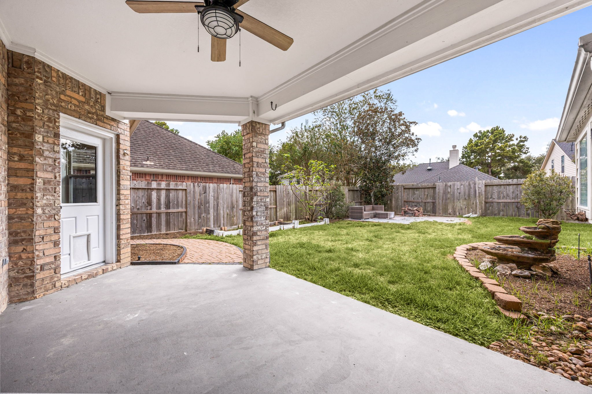 Covered outdoor living area offering a spacious patio with direct access to the grassy backyard.