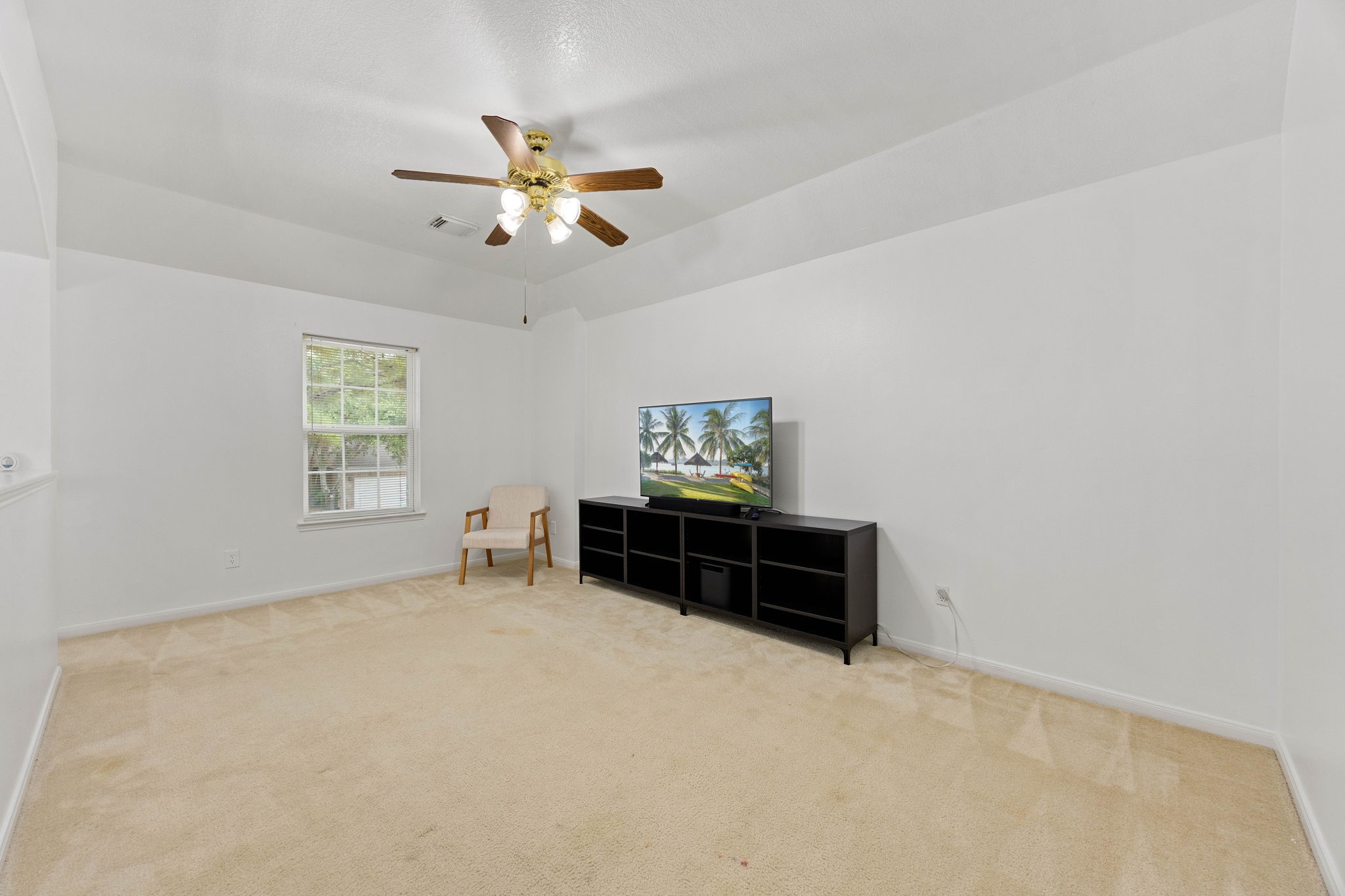 Spacious upstairs game room featuring a ceiling fan, neutral finishes, and flexible space for entertainment or relaxation.