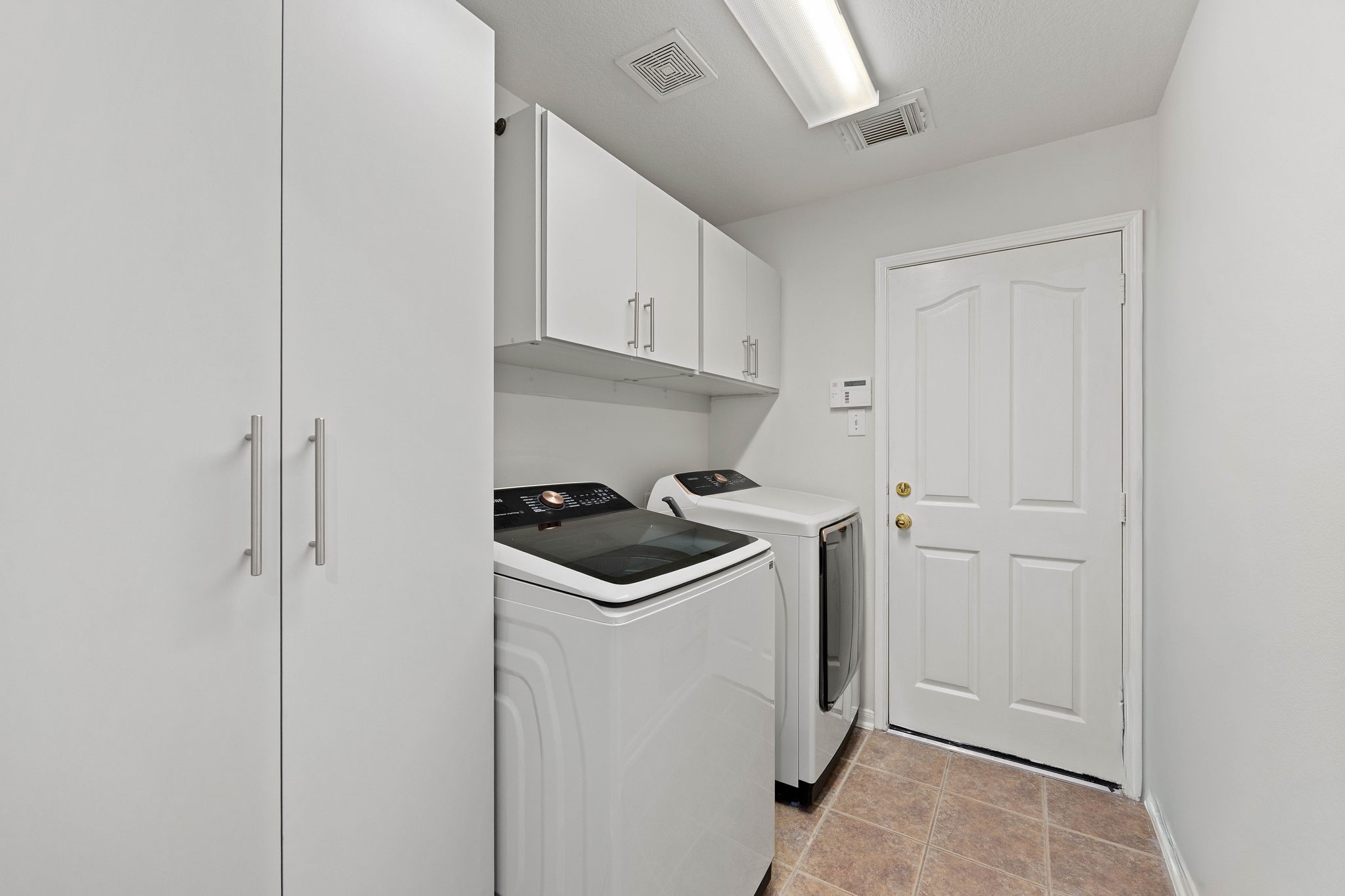 Dedicated laundry room featuring built-in cabinetry and space for a full-size washer and dryer.