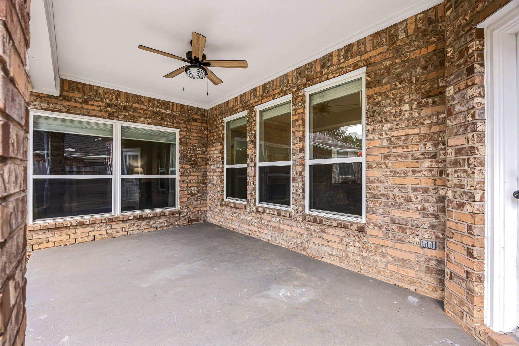 Covered back patio featuring a ceiling fan and generous space for outdoor seating and entertaining.