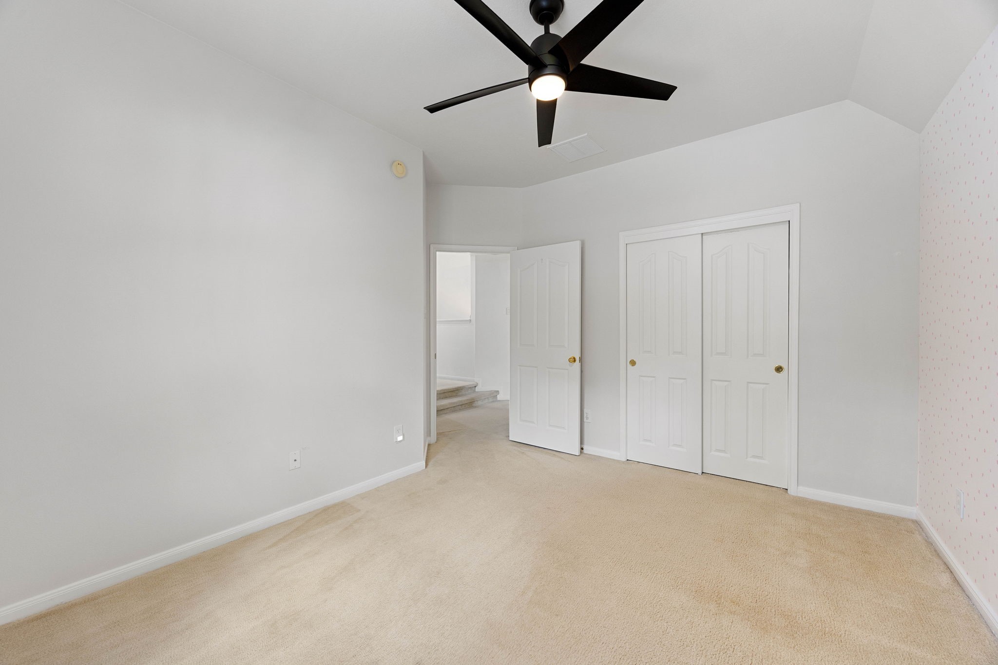 Secondary bedroom (3rd upstairs bedroom) featuring a ceiling fan, neutral finishes, and ample closet storage.