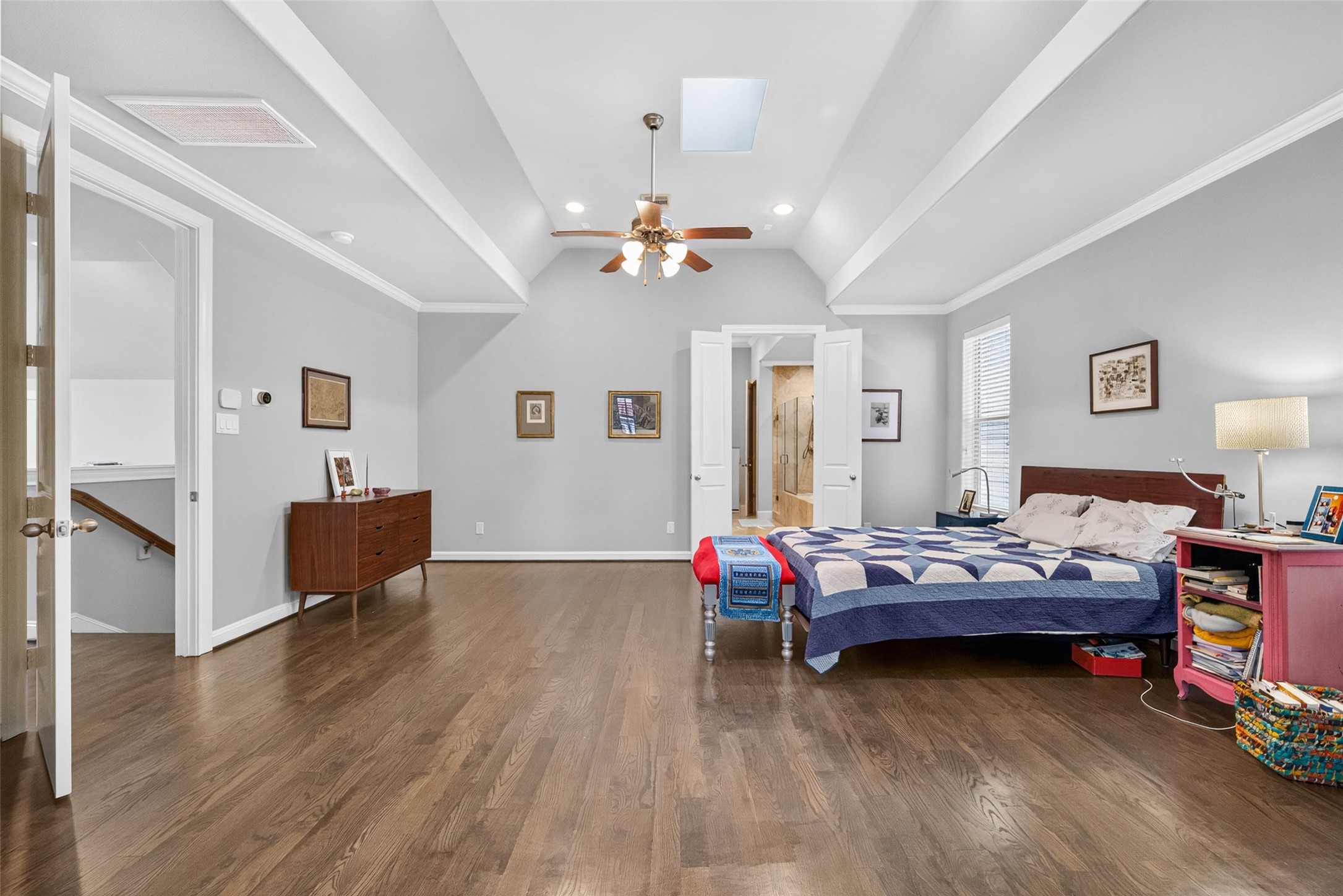 High ceilings create an airy feel in the primary bedroom, with a skylight overhead and ample wall space to display artwork and make the room your own.