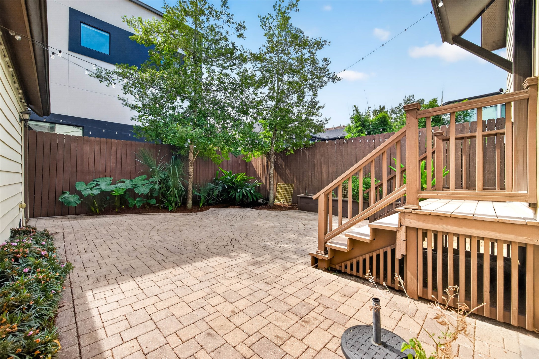 Step outside to a paved backyard bordered by lush greenery, creating a charming and private outdoor space to relax or entertain.
