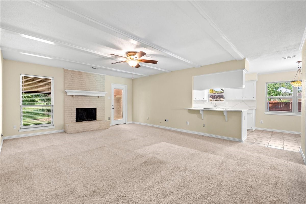 Spacious living area with a cozy brick fireplace, and seamlessly connecting to a bright kitchen, breakfast room and foyer.