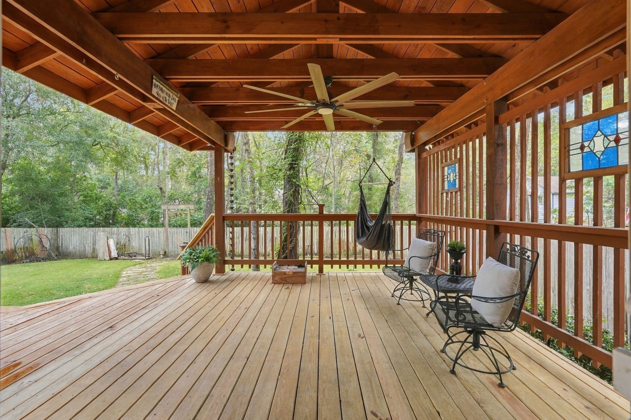 Covered outdoor patio featuring a wood-paneled ceiling, ceiling fan, and plenty of space for relaxing or entertaining.