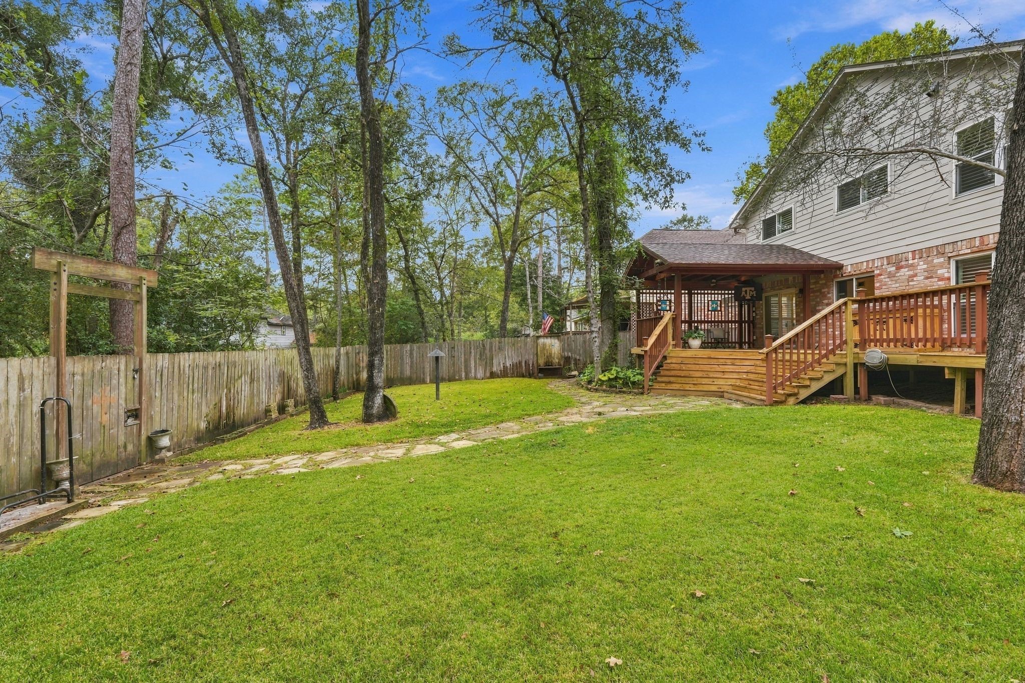 Another view of the expansive backyard, offering plenty of room to relax, play, or entertain. There is a pathway that runs behind the fence on the left- perfect to open your gate and go for a walk or run on the Woodlands trails!