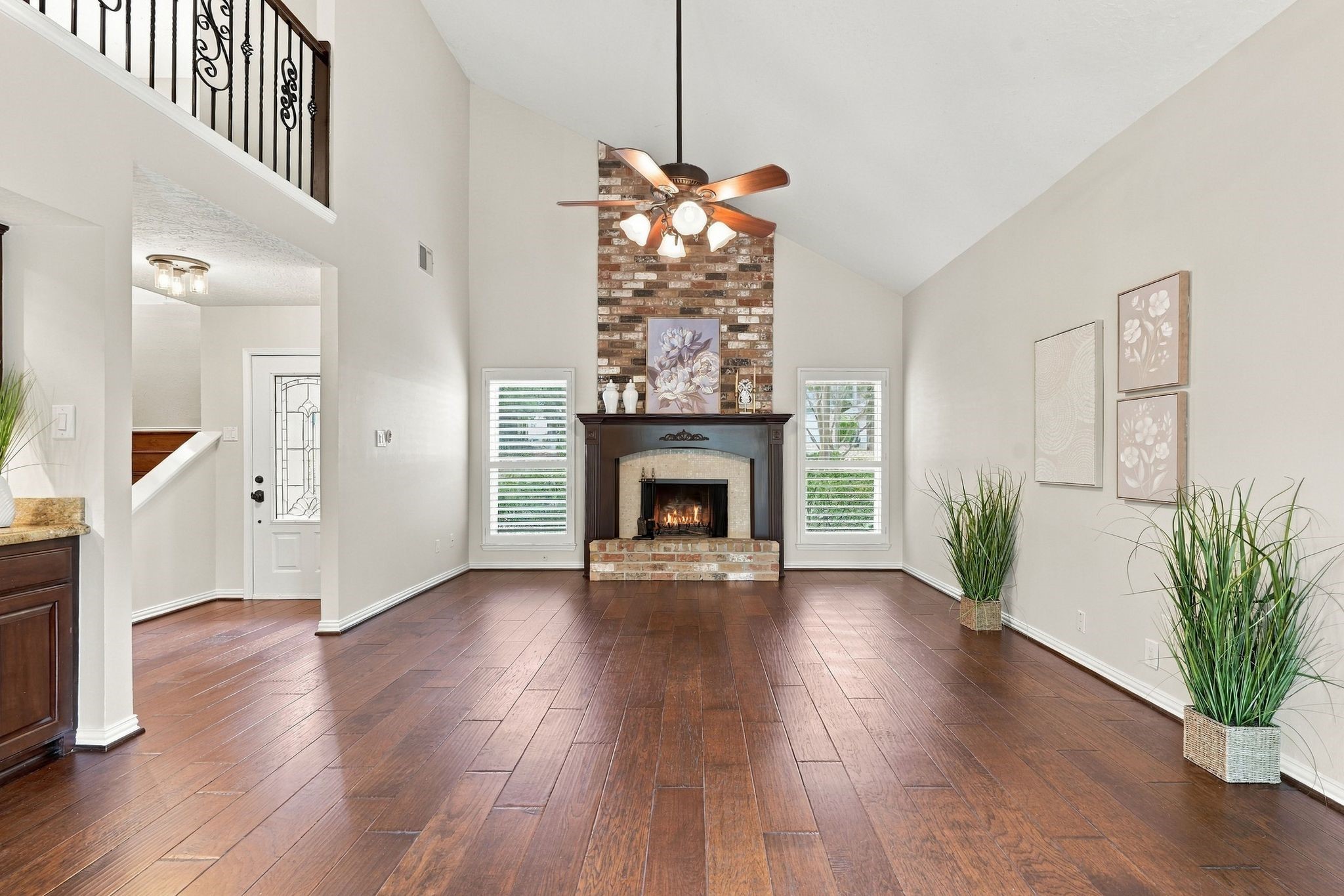 Living room featuring a beautiful wood burning fireplace, soaring ceilings, and an abundance of natural light. This home has Plantation Shutters on all windows. Living room featuring a beautiful wood burning fireplace, soaring ceilings, and an abundance of natural light. This home has Plantation Shutters on all windows.