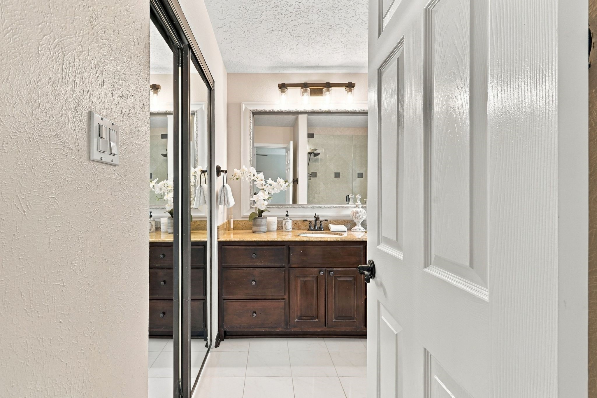 Entrance to the primary bathroom, featuring a granite topped spacious vanity.