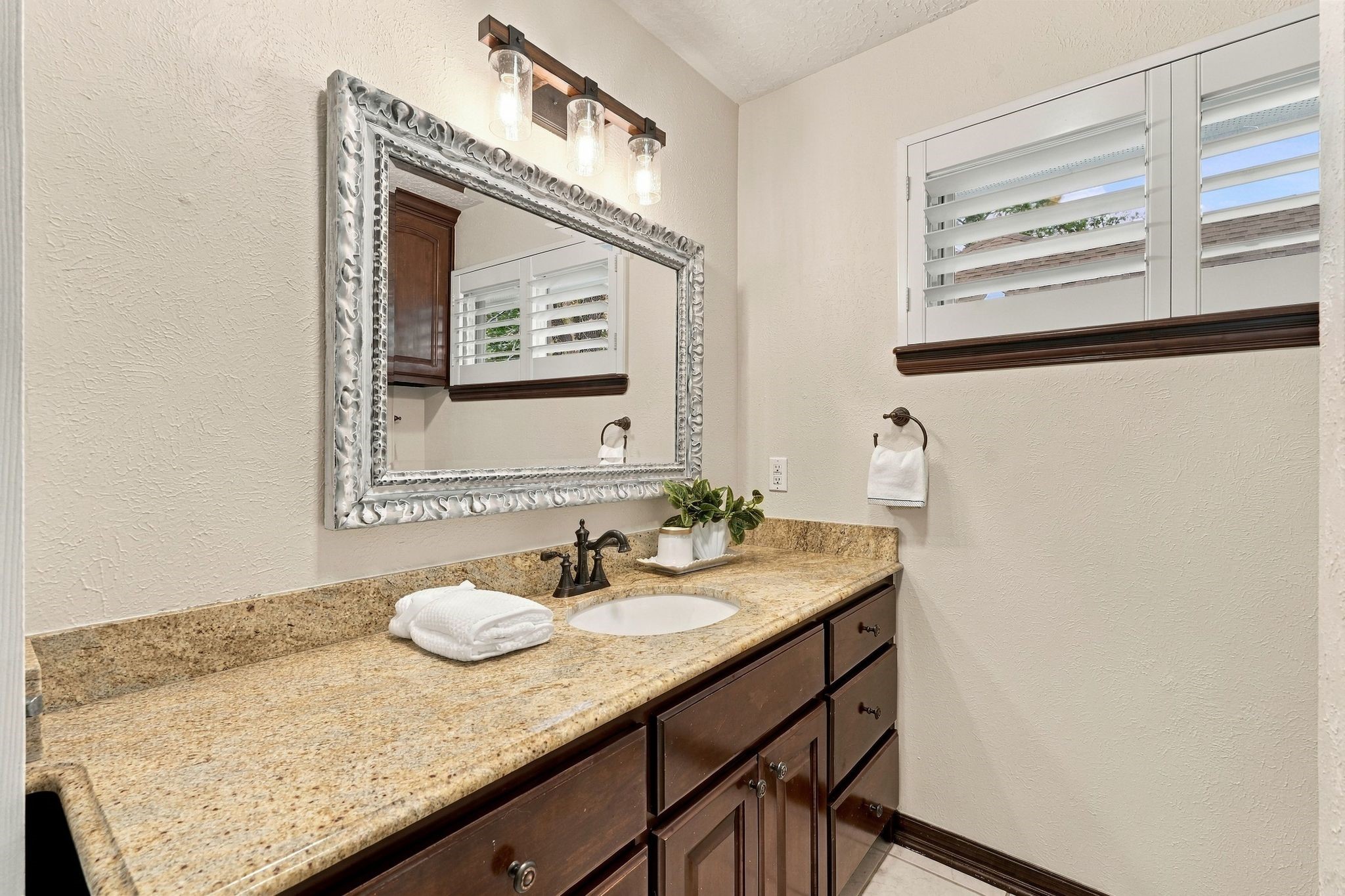 Another view of the bathroom, showcasing the generous counter space, large mirror, and natural light.