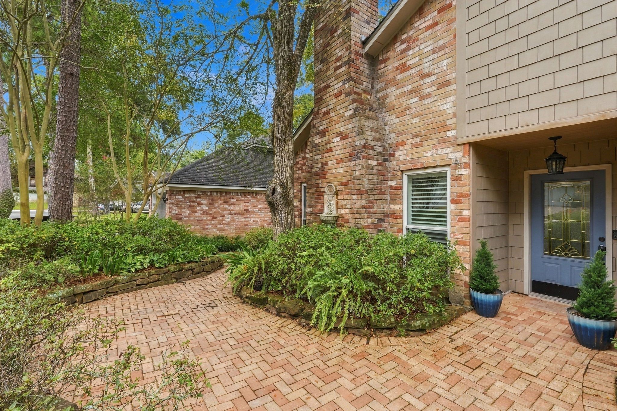 Another view of the home's exterior, highlighting the mature trees, brick accents, and landscaped walkway. Another view of the home's exterior, highlighting the mature trees, brick accents, and landscaped walkway.