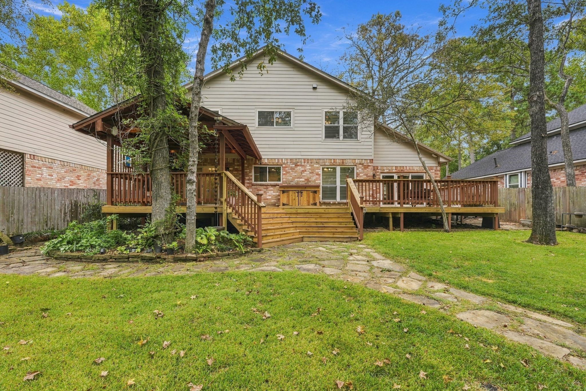 Rear exterior view of the home, highlighting the large wooden deck and beautifully maintained backyard.