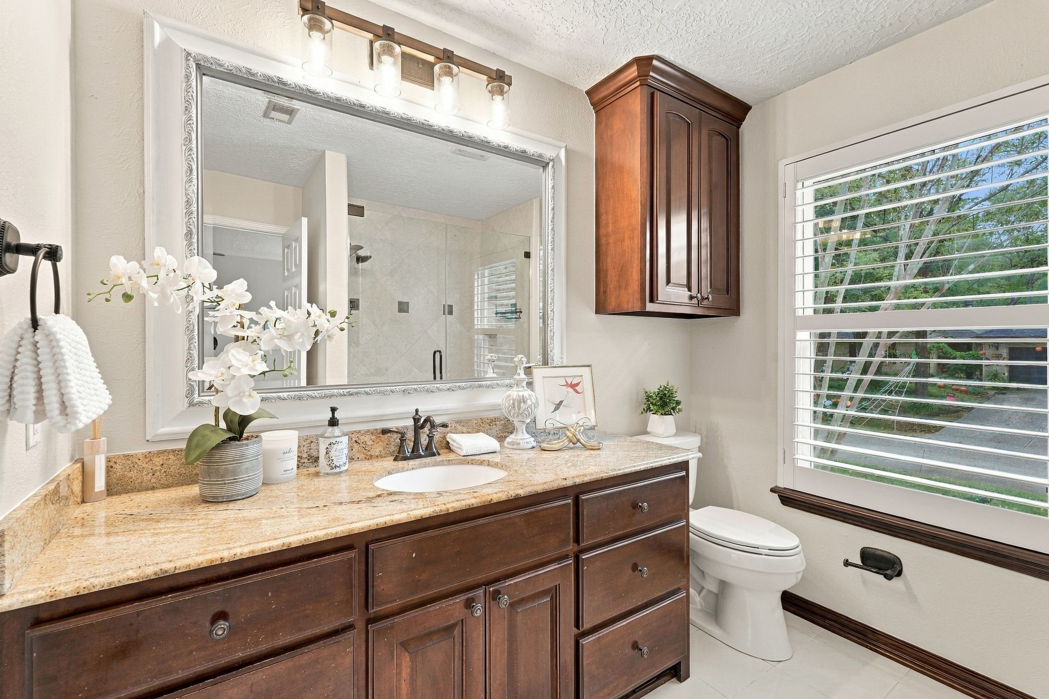 Primary bathroom with generous granite counter space, and large windows bringing in natural light.