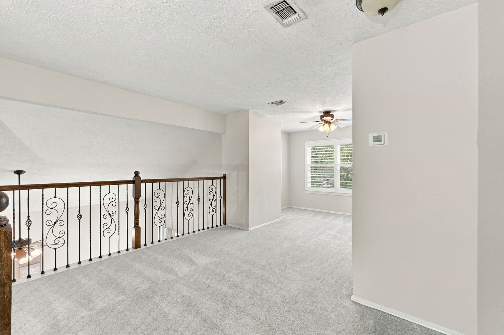 Upstairs loft with a ceiling fan and open railing overlooking the lower level.