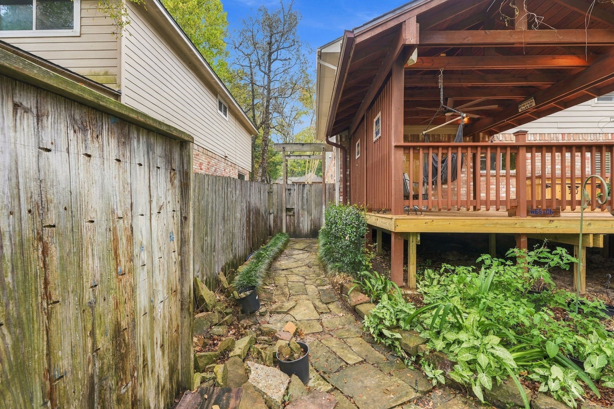 Side yard view showcasing the home's raised deck and surrounding greenery.