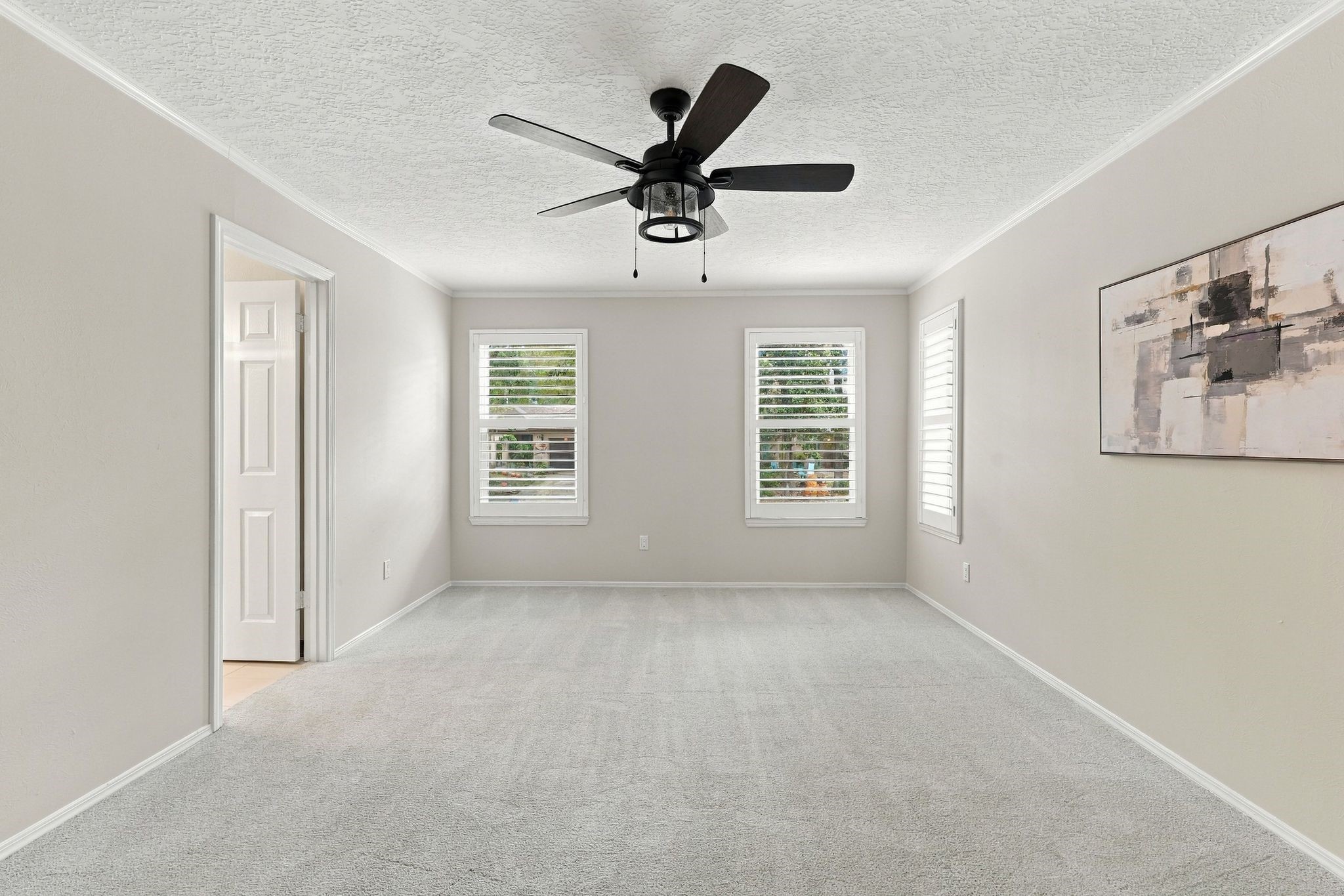 Another angle of the primary bedroom, highlighting its generous space and natural light. Notice the Plantation Shutters - so elegant!
