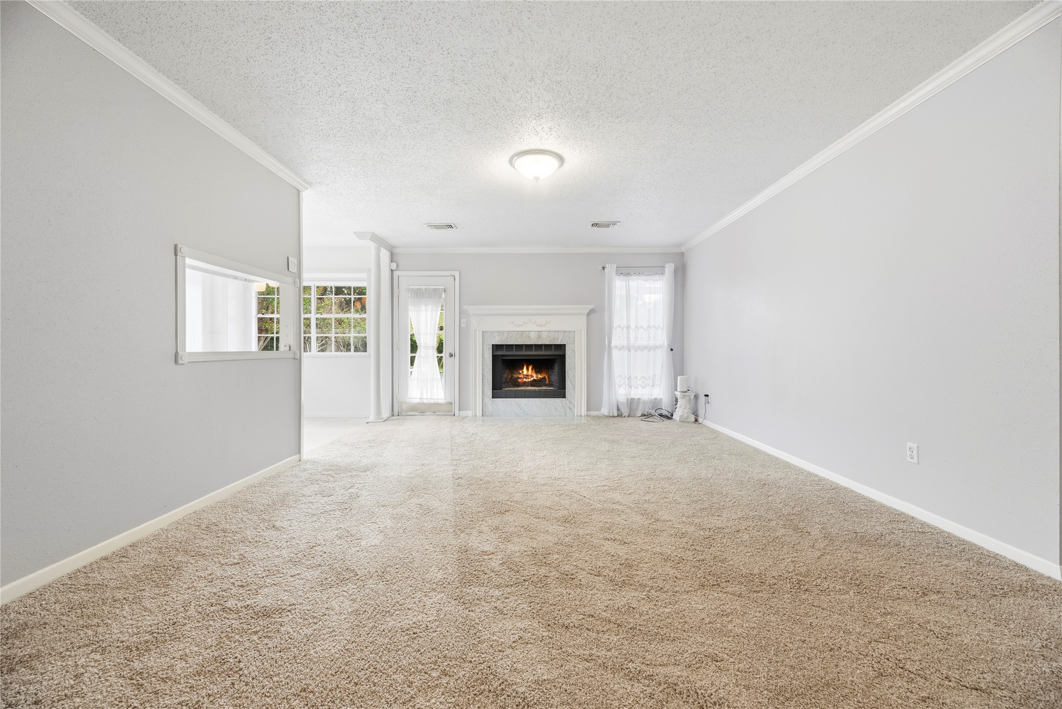 Spacious living room with fresh paint, brand new carpet, fireplace and large windows for natural light.