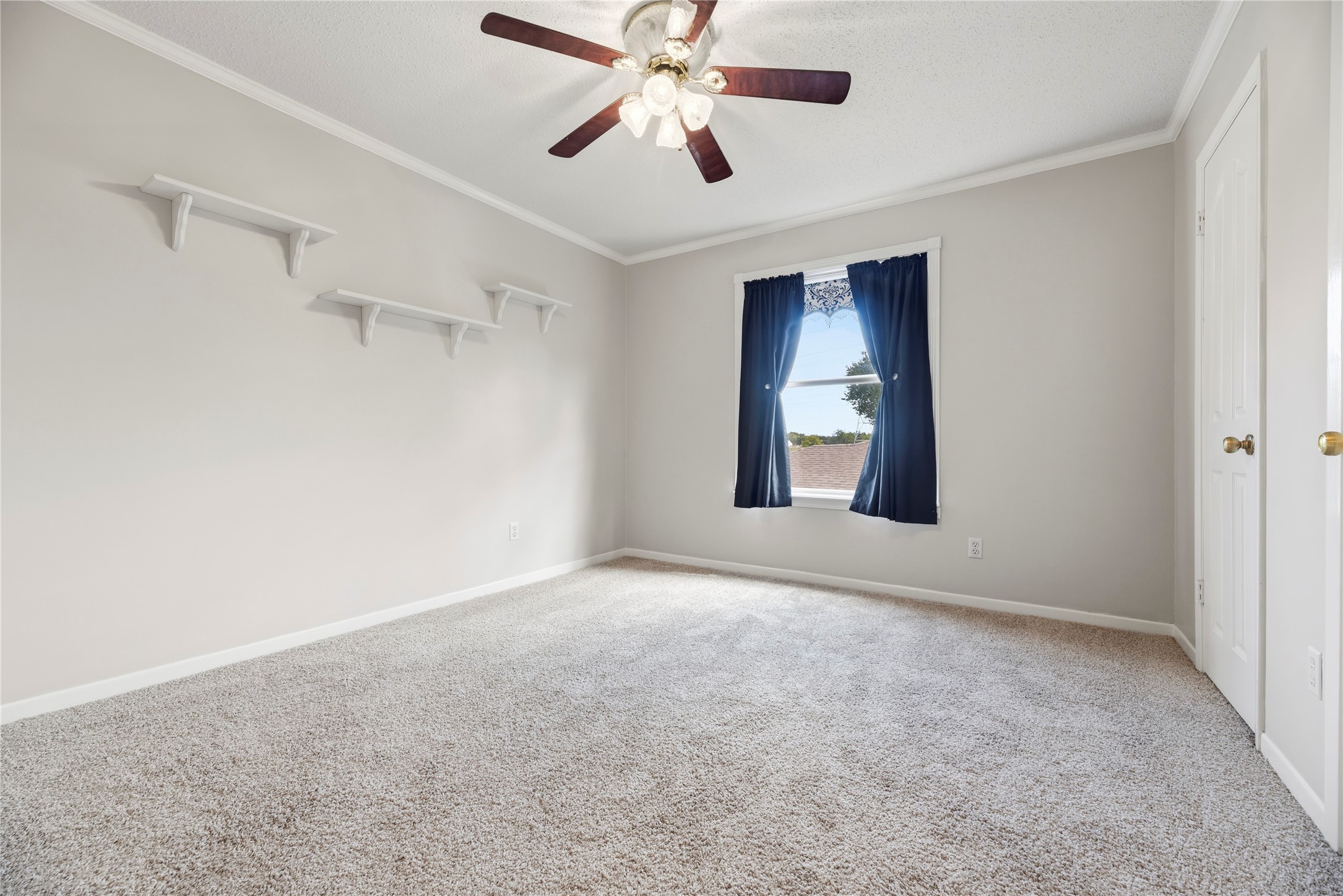 Spacious bedroom located upstairs complete with a ceiling fan and plush carpet.
