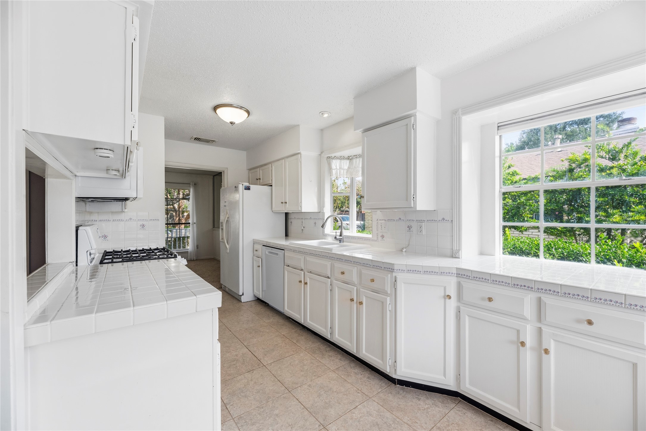 Light and bright kitchen with an abundance of countertop and cabinet space, updated appliances including a gas range.