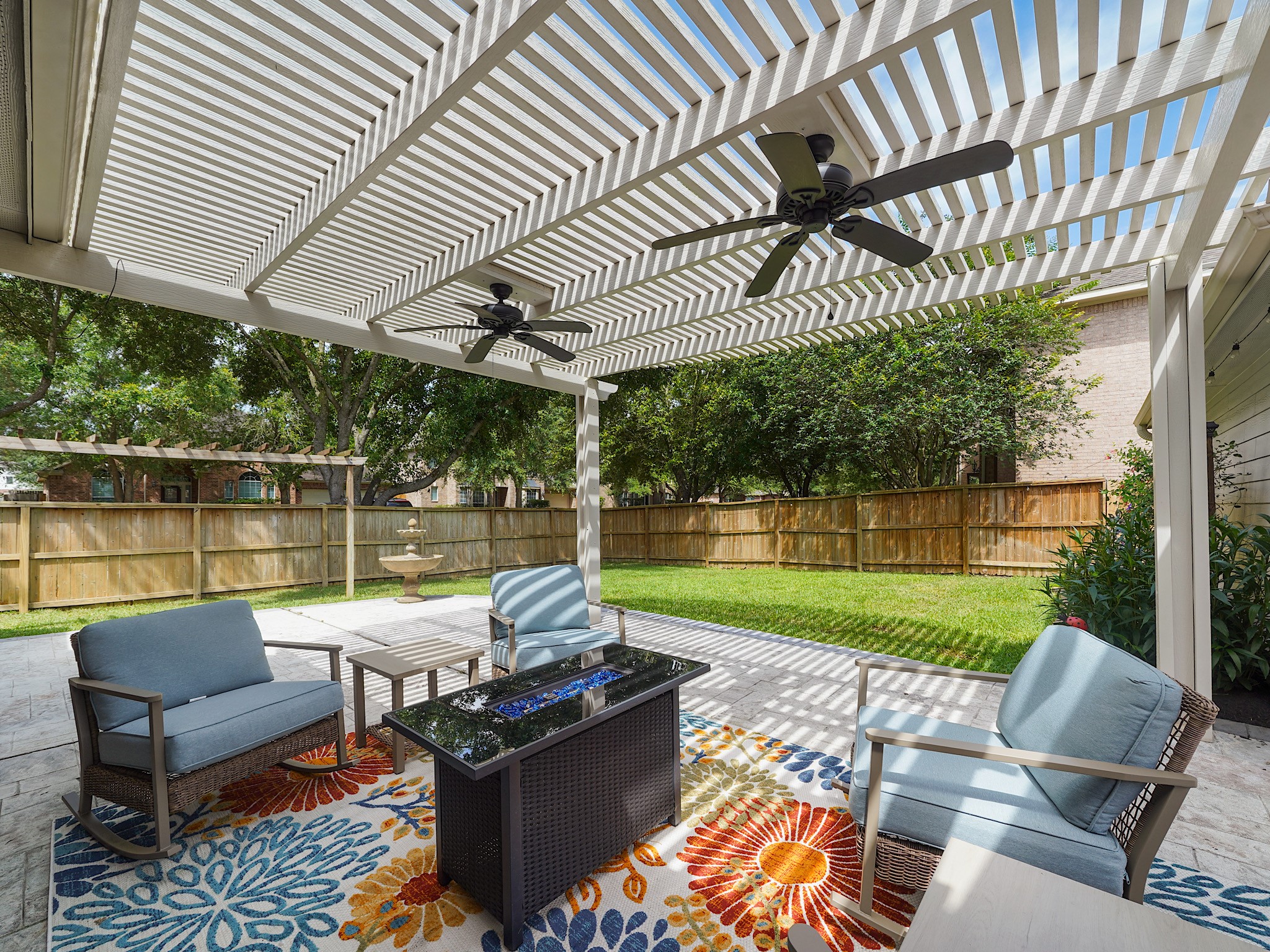 Step outside to an impressive covered patio where ceiling fans, generous seating space, and backyard views create the perfect setting for year-round enjoyment.