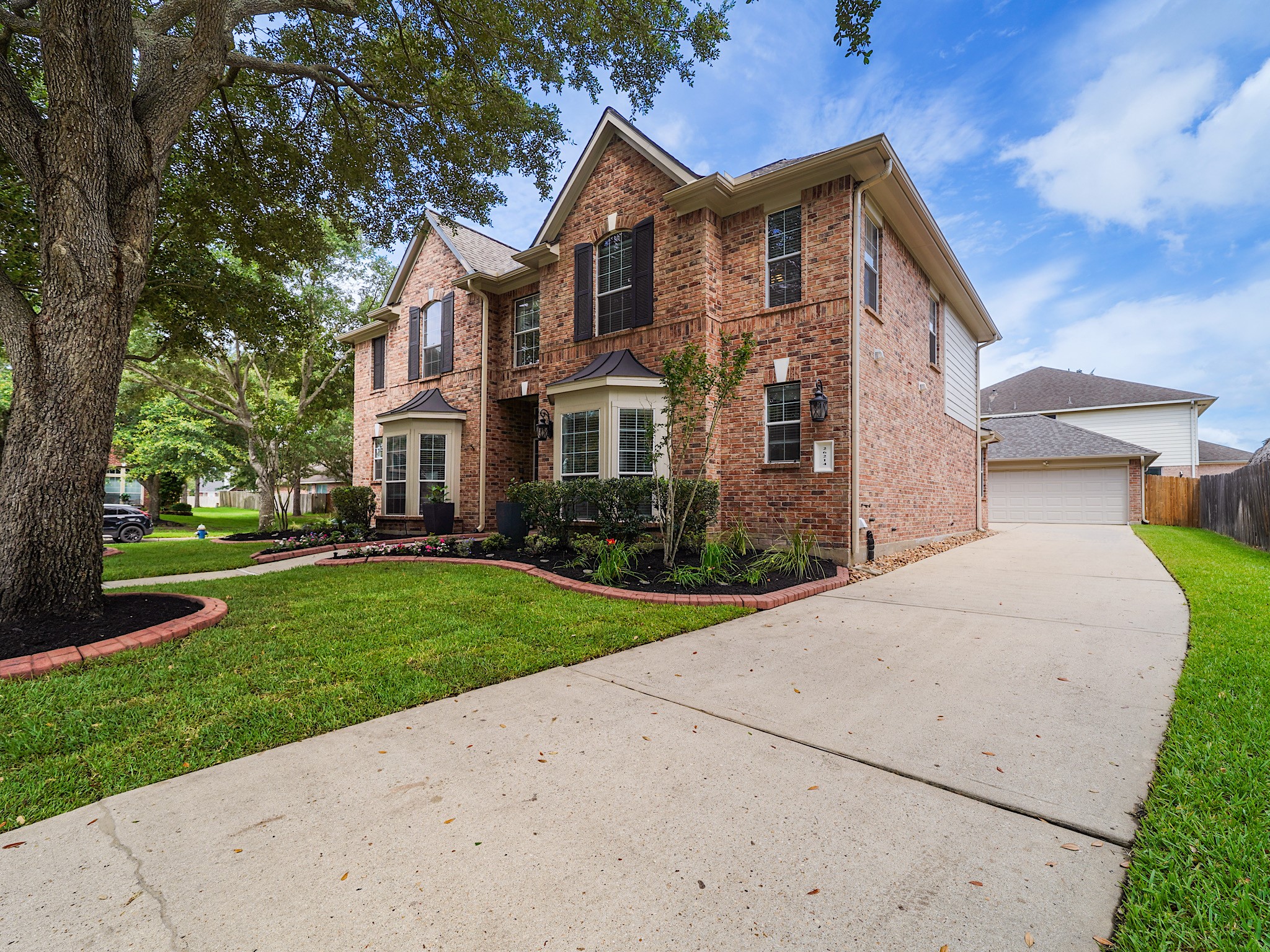 Fresh landscaping, mature shade trees, and timeless brick architecture create a warm welcome and lasting curb appeal.