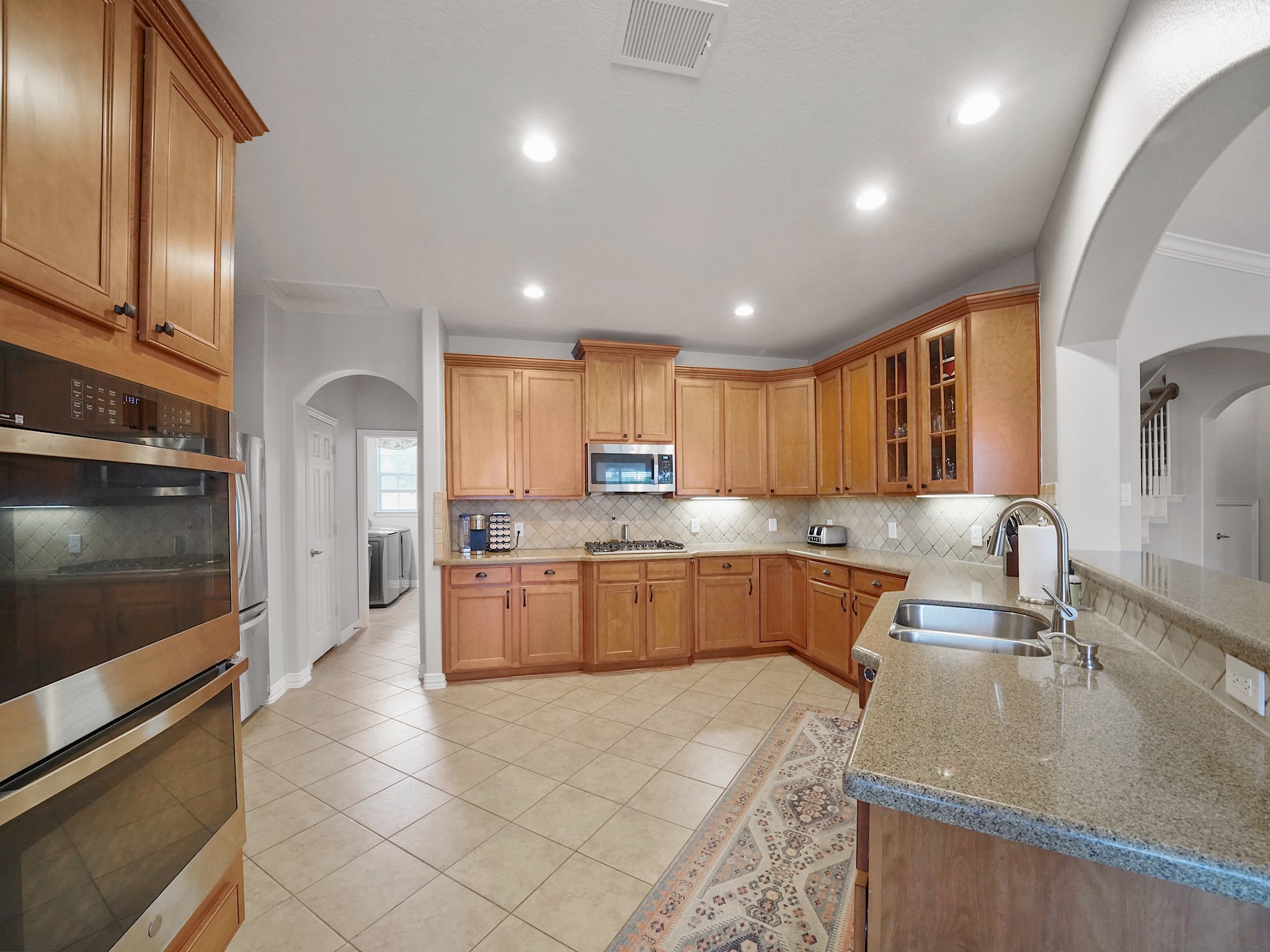 Designed with both beauty and functionality in mind, the kitchen offers granite countertops, double ovens, a gas cooktop, under-cabinet lighting, and abundant workspace for everyday meals and special occasions alike.