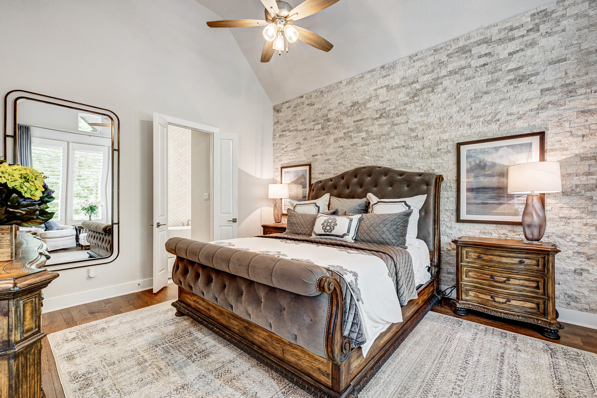 Primary suite features an en suite bathroom oasis and upgraded stone accent wall for texture and design