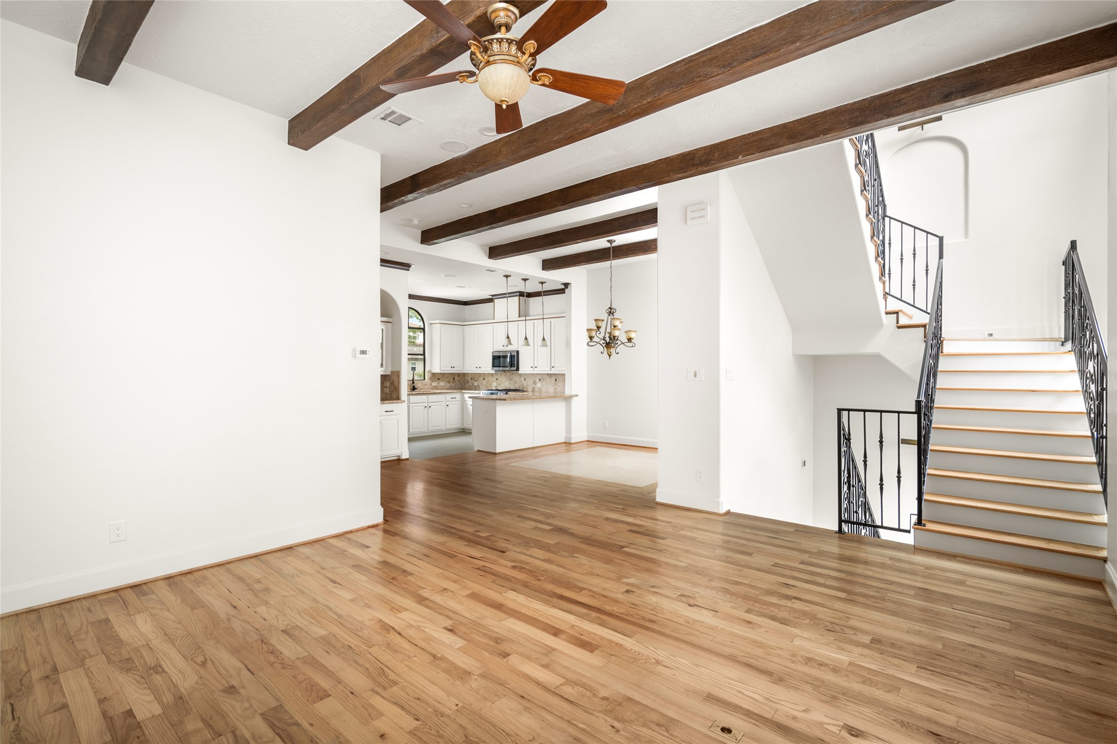 Second level, view of the living room and dining room featuring wood beams and newly refinished hardwood floors.