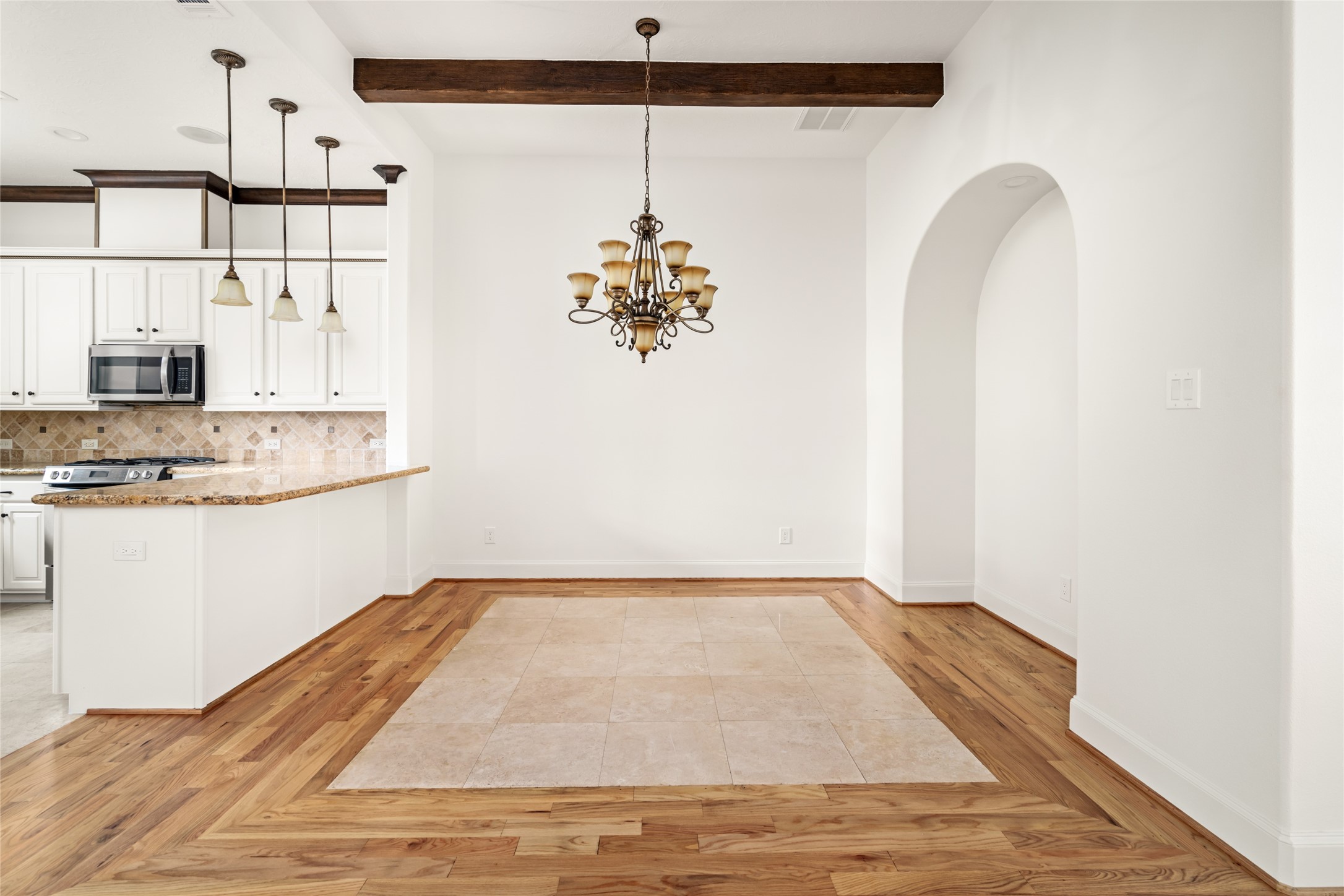 Dining room with exposed wood ceiling beams and a decorative chandelier.