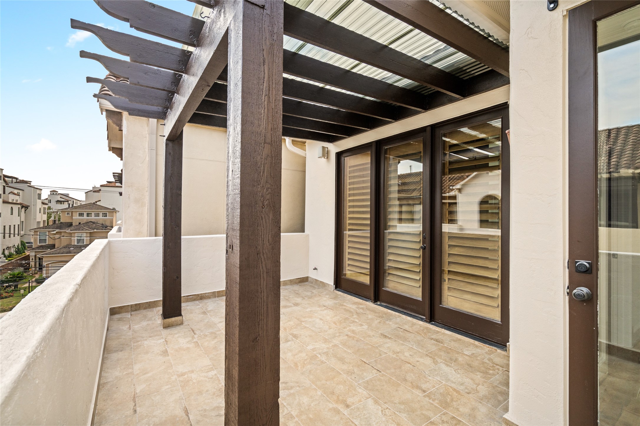 Third floor - Private covered balcony featuring a pergola-style roof, tile flooring, and direct access to the primary suite.