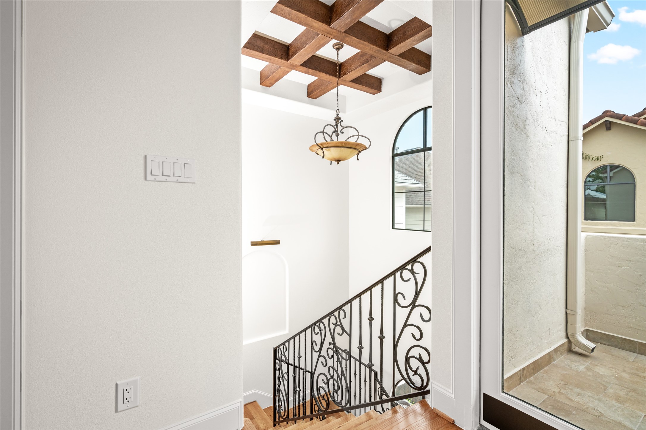 View from the third floor hallway featuring wood beam accent with chandelier.
