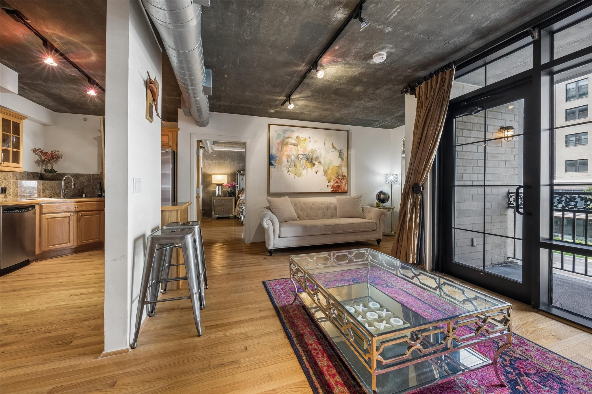 A different perspective of the living area highlights its open design, contemporary finishes, and industrial-inspired ceiling details. The connection between the kitchen and living spaces makes the residence feel welcoming and functional.