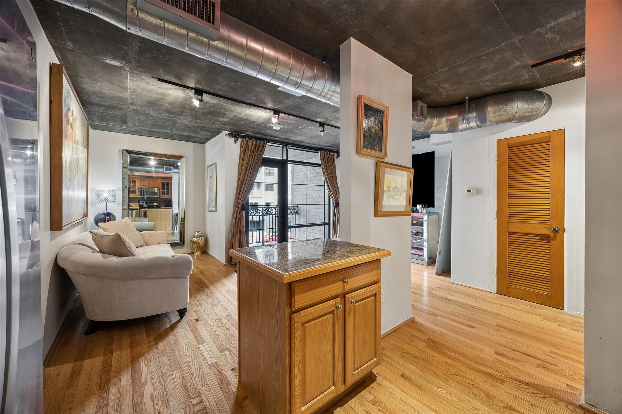 An open-concept layout connects the kitchen and living area, creating a comfortable space for relaxing or entertaining. Hardwood flooring, exposed structural elements, and natural light enhance the home's contemporary character.