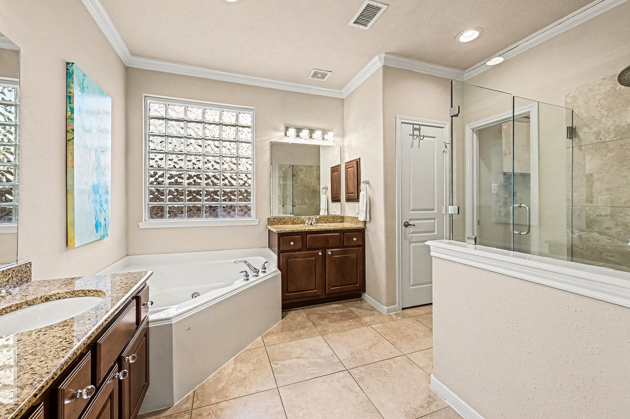 This incredible light and airy Primary bath with his and her vanities with granite countertops, huge walk in glass shower and a corner jetted/soaking tub for those long days to wind down.