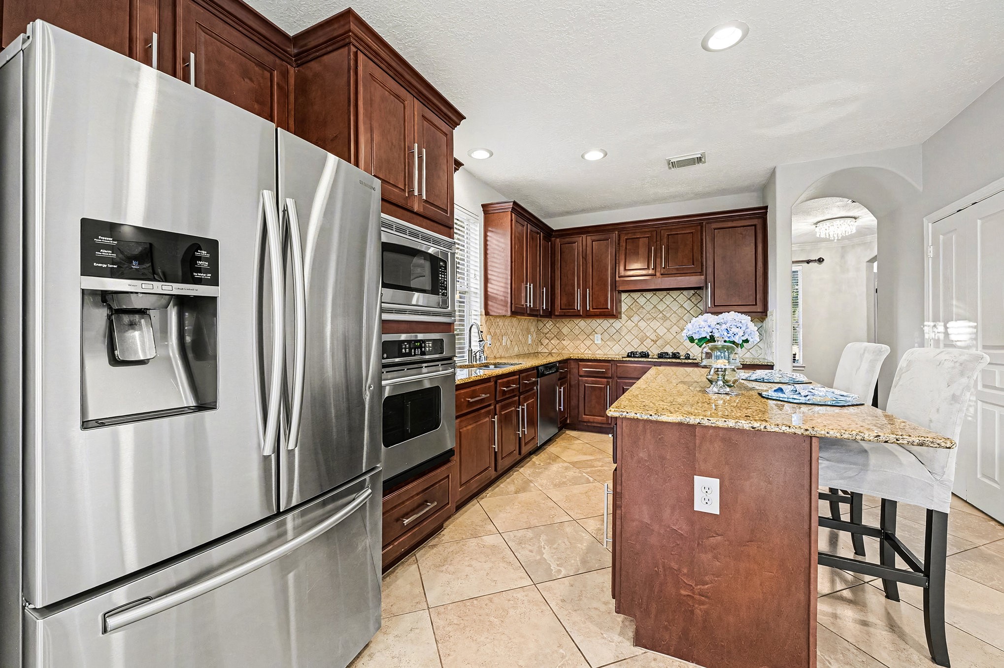 This is a chef's dream kitchen which features rich all wood cabinets by Kent Moore, stainless appliances, granite counters, island with seating and diagonally laid tile. Open to Family room and breakfast area.