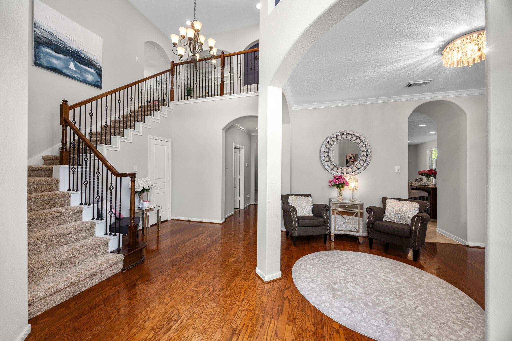 Step inside the Grand Foyer to find fresh neutral paint & elegant wood floors.
The grand foyer makes a striking first impression with its sweeping curved staircase, adorned with wrought iron balusters and a rich wood handrail. Shows a very inviting seating area in dining room.