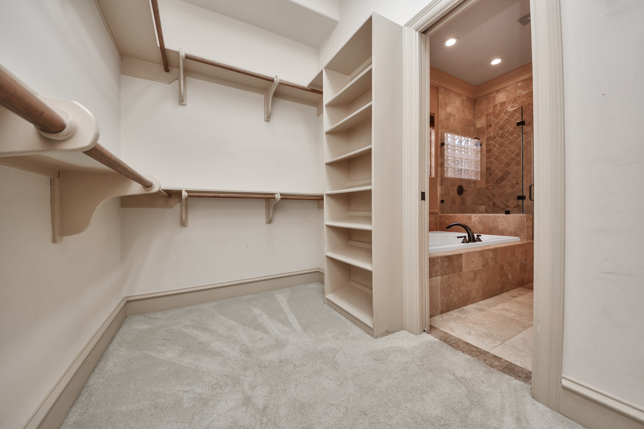 Primary walk in closet with lots of space for organizing shoes, purses and etc.